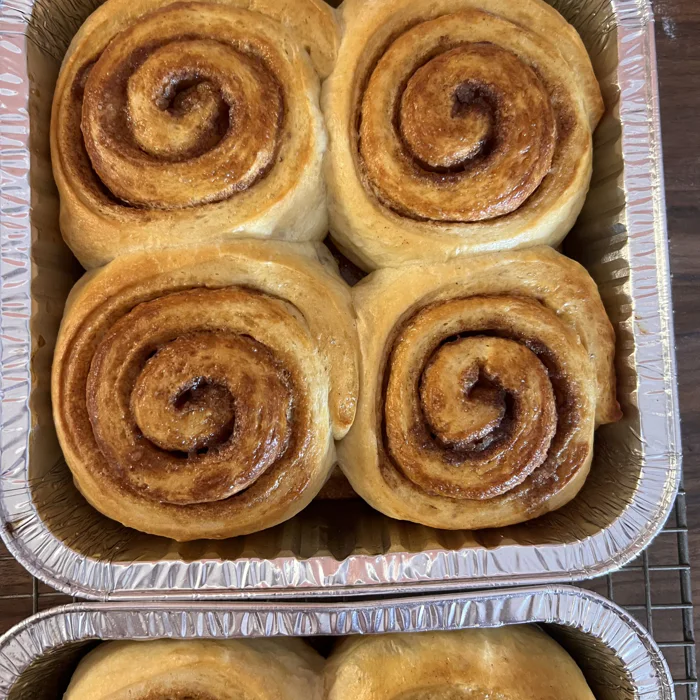 Four glazed cinnamon swirls, baked together in a pan